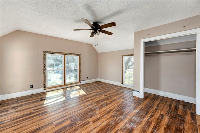 unfurnished bedroom with wood finished floors, baseboards, vaulted ceiling, a closet, and a textured ceiling