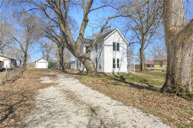 view of front of home featuring a detached garage, an outdoor structure, driveway, and fence