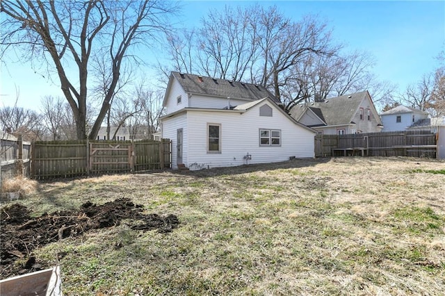 rear view of property featuring a lawn and a fenced backyard