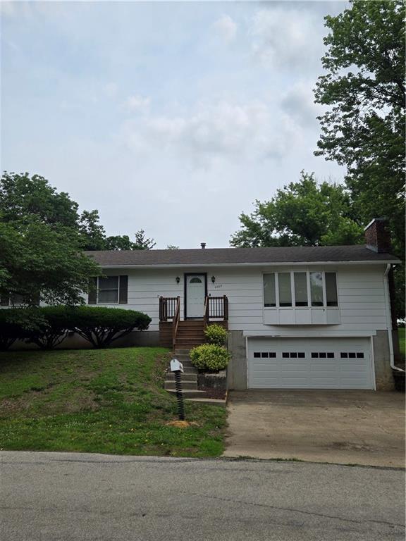 2213 Millwood Dr, Atchison, KS 66002 - view of front facade with a garage, concrete driveway, and a chimney