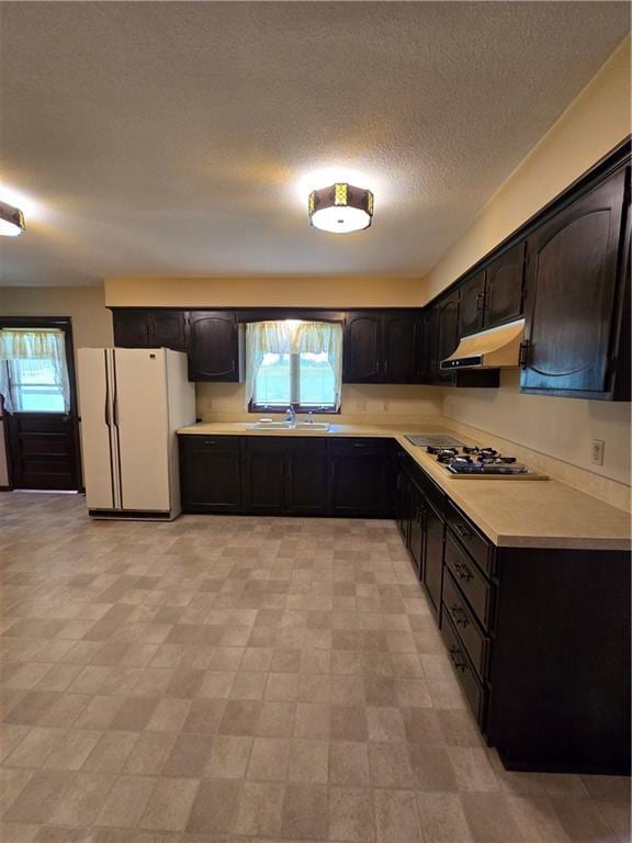 2213 Millwood Dr, Atchison, KS 66002 - kitchen with freestanding refrigerator, stainless steel gas cooktop, under cabinet range hood, light countertops, and a textured ceiling