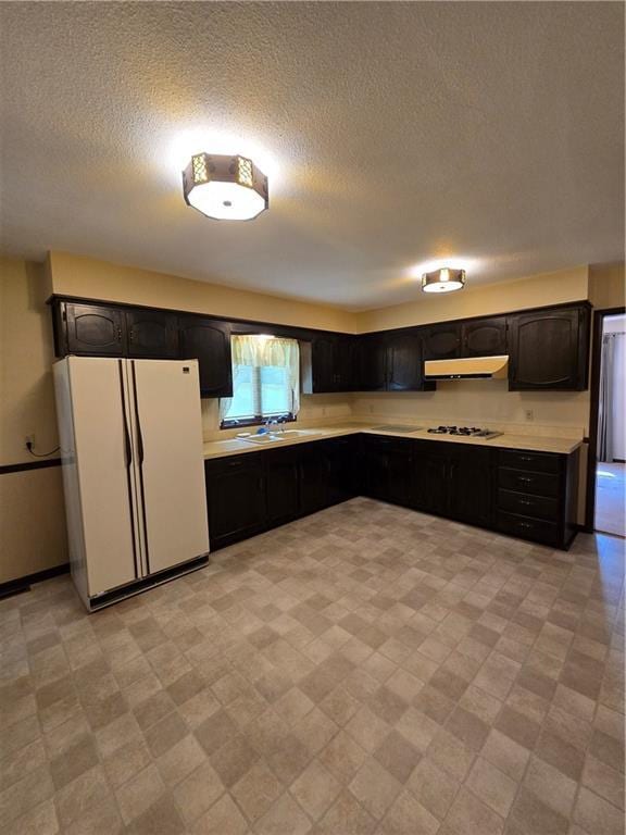 2213 Millwood Dr, Atchison, KS 66002 - kitchen with freestanding refrigerator, under cabinet range hood, light countertops, gas cooktop, and a textured ceiling