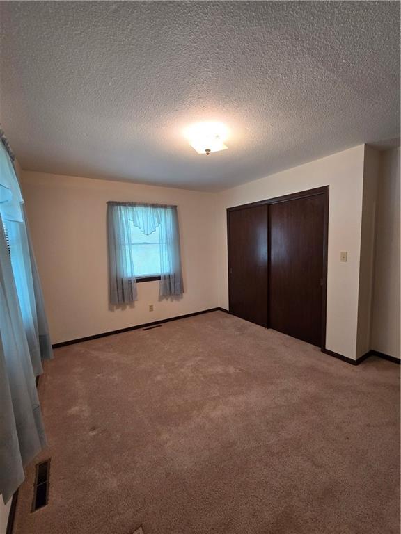 2213 Millwood Dr, Atchison, KS 66002 - unfurnished bedroom featuring light carpet, a textured ceiling, and a closet