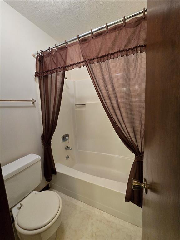 2213 Millwood Dr, Atchison, KS 66002 - full bath featuring shower / tub combo with curtain and a textured ceiling