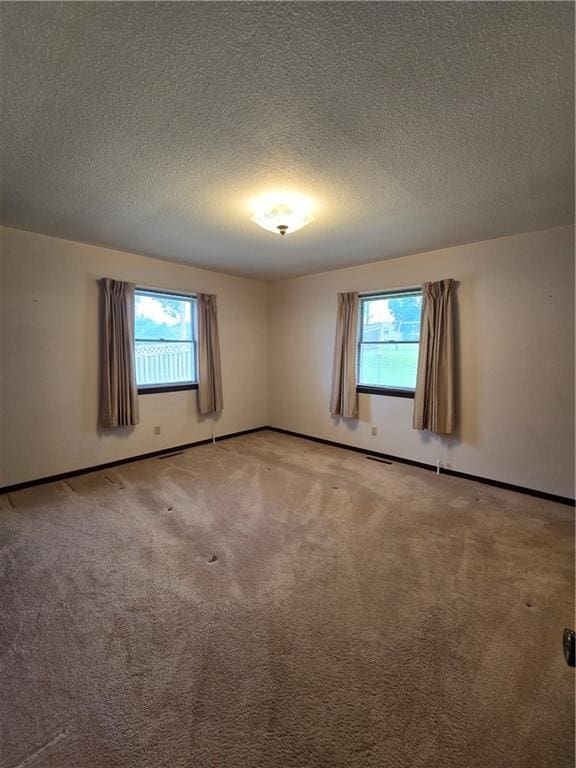 2213 Millwood Dr, Atchison, KS 66002 - empty room featuring light carpet, plenty of natural light, and a textured ceiling