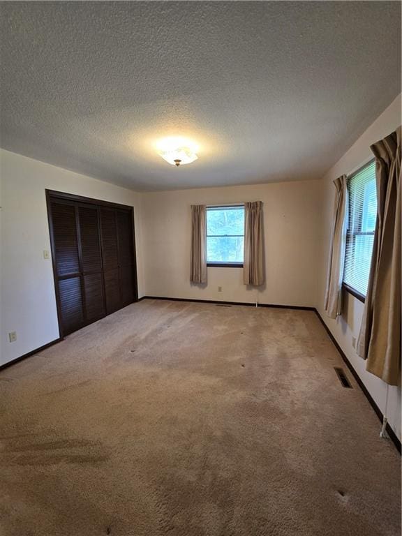 2213 Millwood Dr, Atchison, KS 66002 - unfurnished bedroom featuring light carpet, a textured ceiling, and a closet