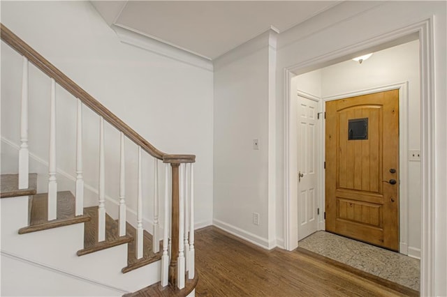 entryway with stairway, wood finished floors, baseboards, and ornamental molding