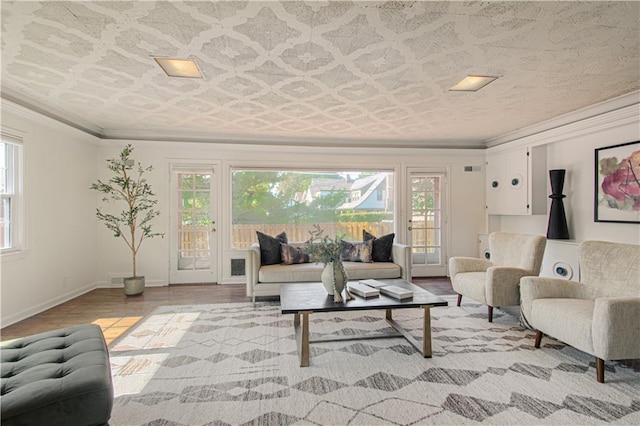 living area with baseboards, wood finished floors, and crown molding