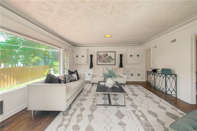 living room with visible vents, crown molding, baseboards, and wood finished floors