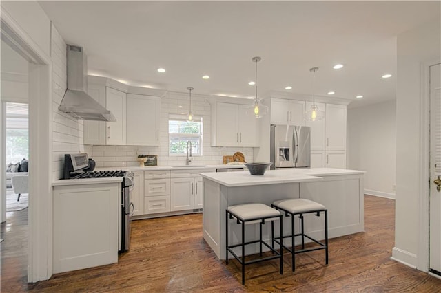 kitchen with dark wood finished floors, extractor fan, white cabinets, appliances with stainless steel finishes, and a center island