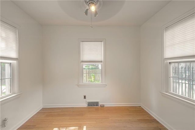 unfurnished room featuring a ceiling fan, visible vents, light wood finished floors, and baseboards