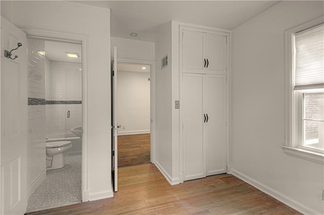 unfurnished bedroom with visible vents, light wood-style flooring, ensuite bath, a closet, and baseboards