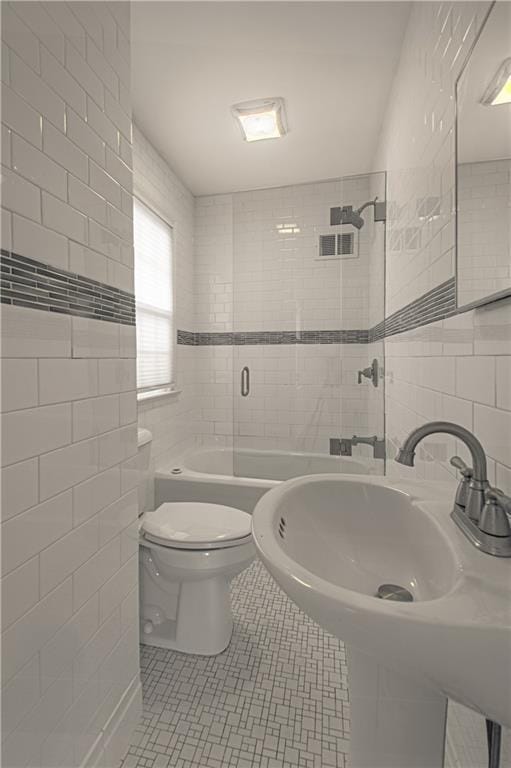 bathroom featuring shower / bathing tub combination, a sink, tile patterned flooring, tile walls, and toilet