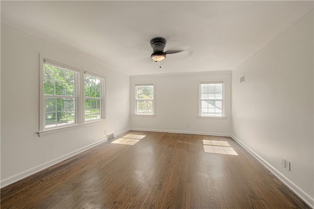 spare room with a ceiling fan, wood finished floors, visible vents, and baseboards