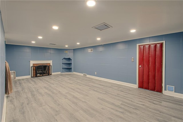 unfurnished living room with a brick fireplace, recessed lighting, wood finished floors, and visible vents