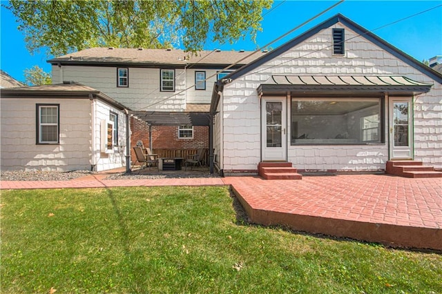 back of property with entry steps, a patio area, a standing seam roof, and a lawn