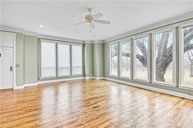 unfurnished living room featuring light wood-style flooring, baseboards, ornamental molding, and a ceiling fan