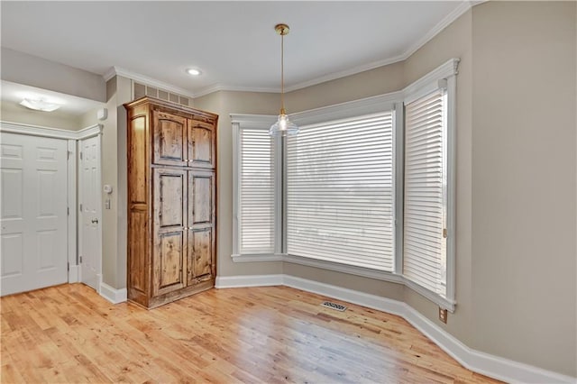 unfurnished dining area with crown molding, light wood-style floors, and baseboards