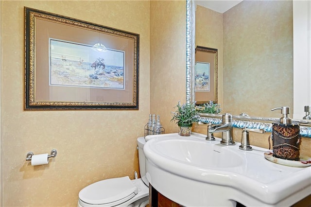 half bath featuring toilet, vanity, and a textured wall