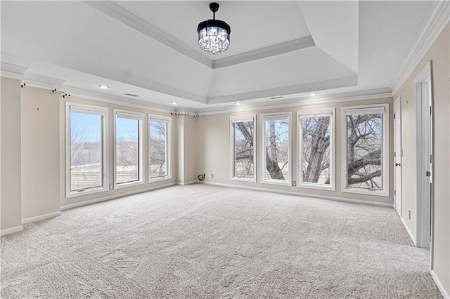 carpeted empty room with a raised ceiling, a notable chandelier, recessed lighting, crown molding, and baseboards