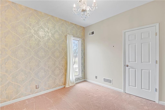 carpeted spare room featuring baseboards, visible vents, and a chandelier