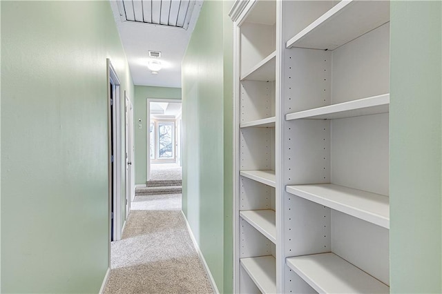 hallway with visible vents, baseboards, and carpet flooring