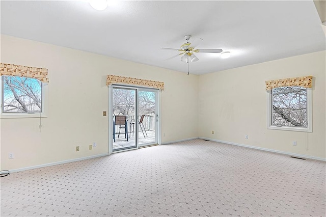 spare room with visible vents, baseboards, light colored carpet, and ceiling fan