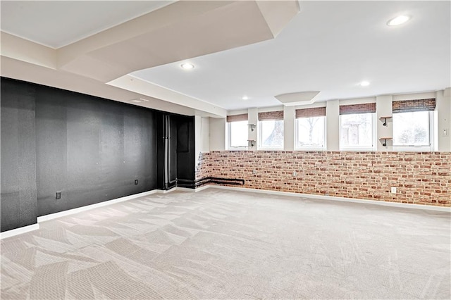 spare room featuring recessed lighting, light colored carpet, brick wall, and baseboards