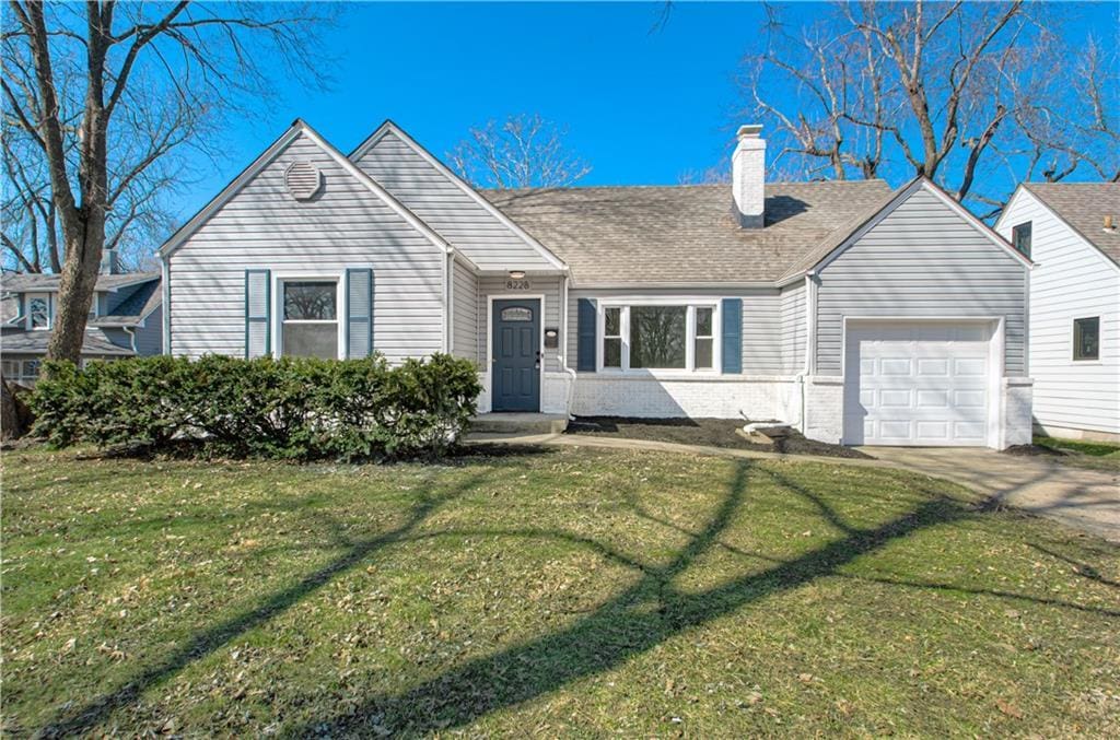 single story home featuring concrete driveway, a front yard, a garage, brick siding, and a chimney