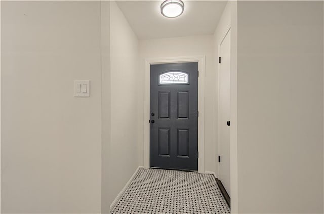 doorway to outside featuring light floors and baseboards