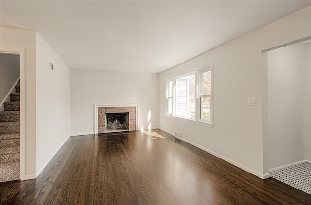 unfurnished living room with dark wood finished floors, stairway, a fireplace, and baseboards