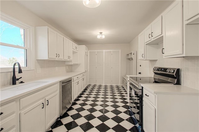 kitchen featuring light floors, light countertops, stainless steel appliances, white cabinetry, and a sink