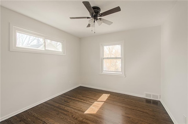 unfurnished room featuring dark wood-style floors, visible vents, and baseboards