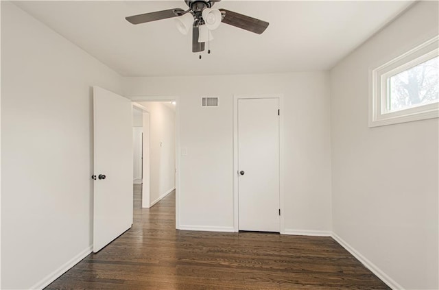 unfurnished bedroom with a ceiling fan, dark wood-style floors, visible vents, and baseboards