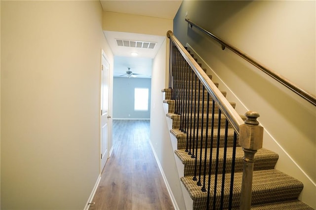 stairs featuring ceiling fan, visible vents, baseboards, and wood finished floors