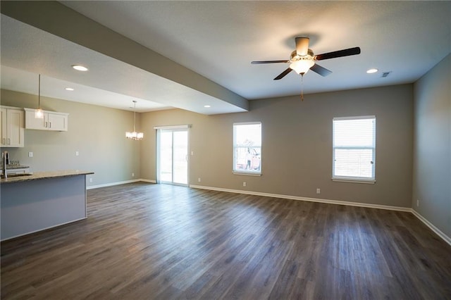 unfurnished living room featuring dark wood-style floors, recessed lighting, ceiling fan with notable chandelier, and baseboards