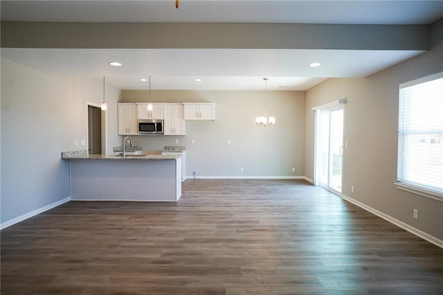 kitchen featuring stainless steel microwave, dark wood-style floors, white cabinetry, recessed lighting, and an inviting chandelier