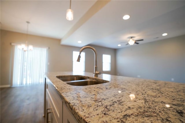 kitchen with pendant lighting, light stone counters, recessed lighting, and a sink