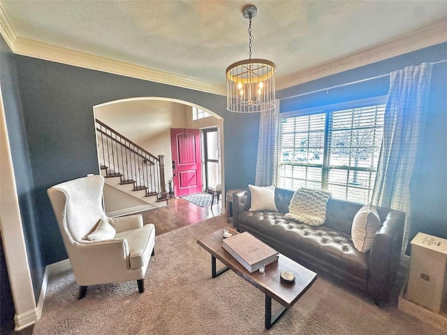 living room with ornamental molding, a textured ceiling, stairway, arched walkways, and a chandelier