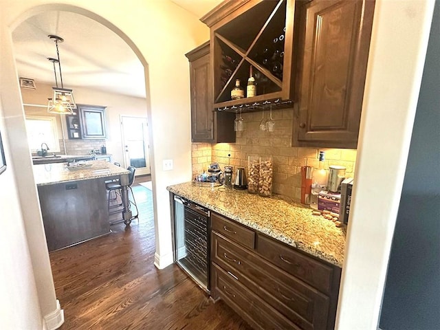 bar with decorative backsplash, wine cooler, arched walkways, and dark wood-style floors