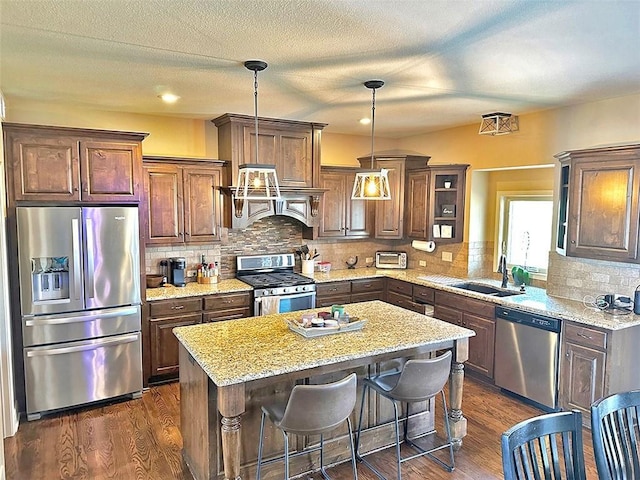 kitchen featuring a center island, dark wood-style flooring, stainless steel appliances, and a sink