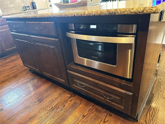 interior details featuring dark wood-type flooring, backsplash, and oven