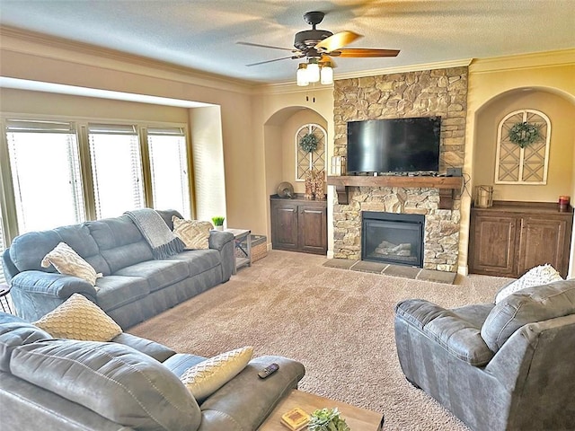 carpeted living room featuring a textured ceiling, a ceiling fan, a fireplace, and ornamental molding