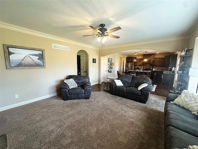 living room with visible vents, arched walkways, baseboards, and crown molding