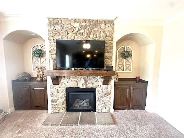 unfurnished living room featuring a fireplace, crown molding, and carpet floors