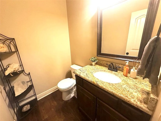 bathroom featuring vanity, toilet, wood finished floors, and baseboards