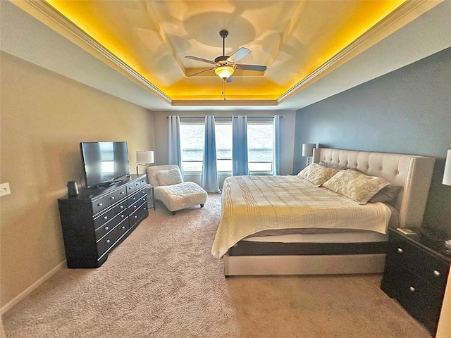 bedroom with crown molding, ceiling fan, baseboards, a tray ceiling, and carpet floors