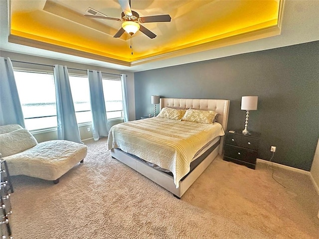 carpeted bedroom with baseboards, a raised ceiling, visible vents, and a ceiling fan