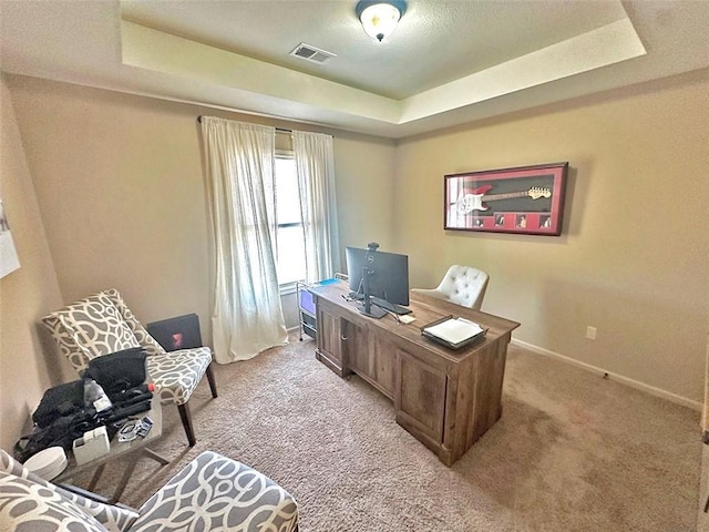 office area featuring a raised ceiling, baseboards, visible vents, and light carpet