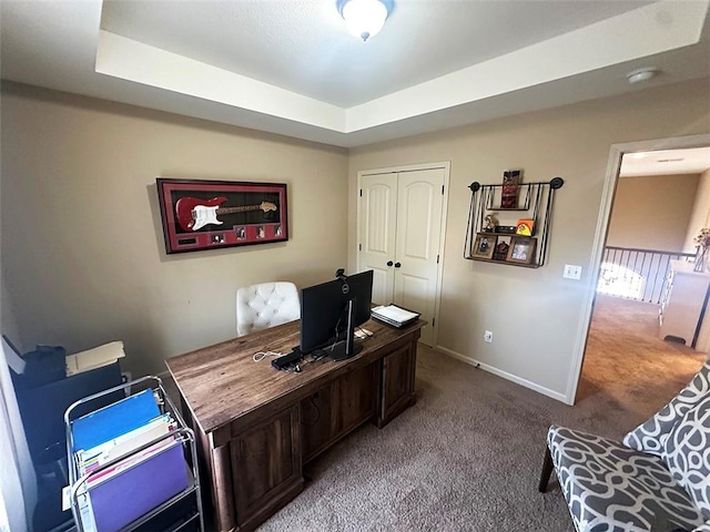 carpeted home office featuring baseboards and a raised ceiling